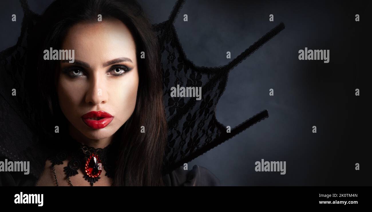 Halloween Vampire Woman portrait. Beautiful Glamour Fashion Sexy Vampire Lady with long black hair, beauty make up and costume Stock Photo