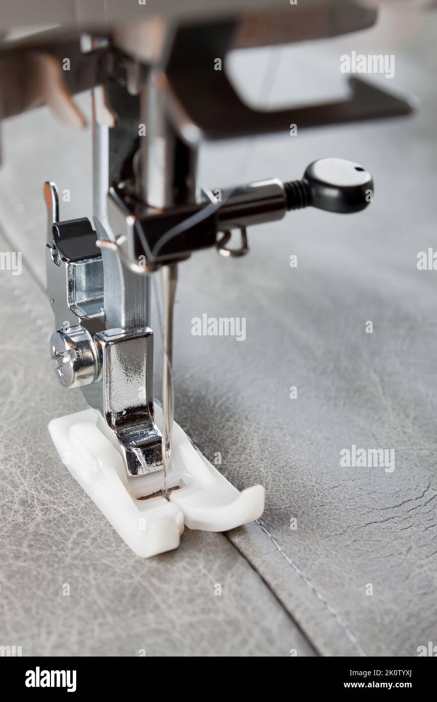 Man's feet at pedal of industrial sewing machine stock photo - OFFSET