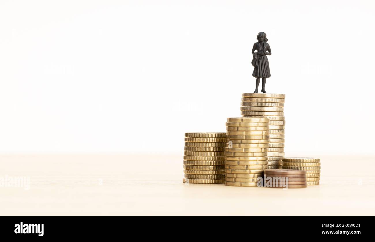 Wealth, making money, wage growth concept. Woman figurine standing on a pile of coins. Copy space Stock Photo