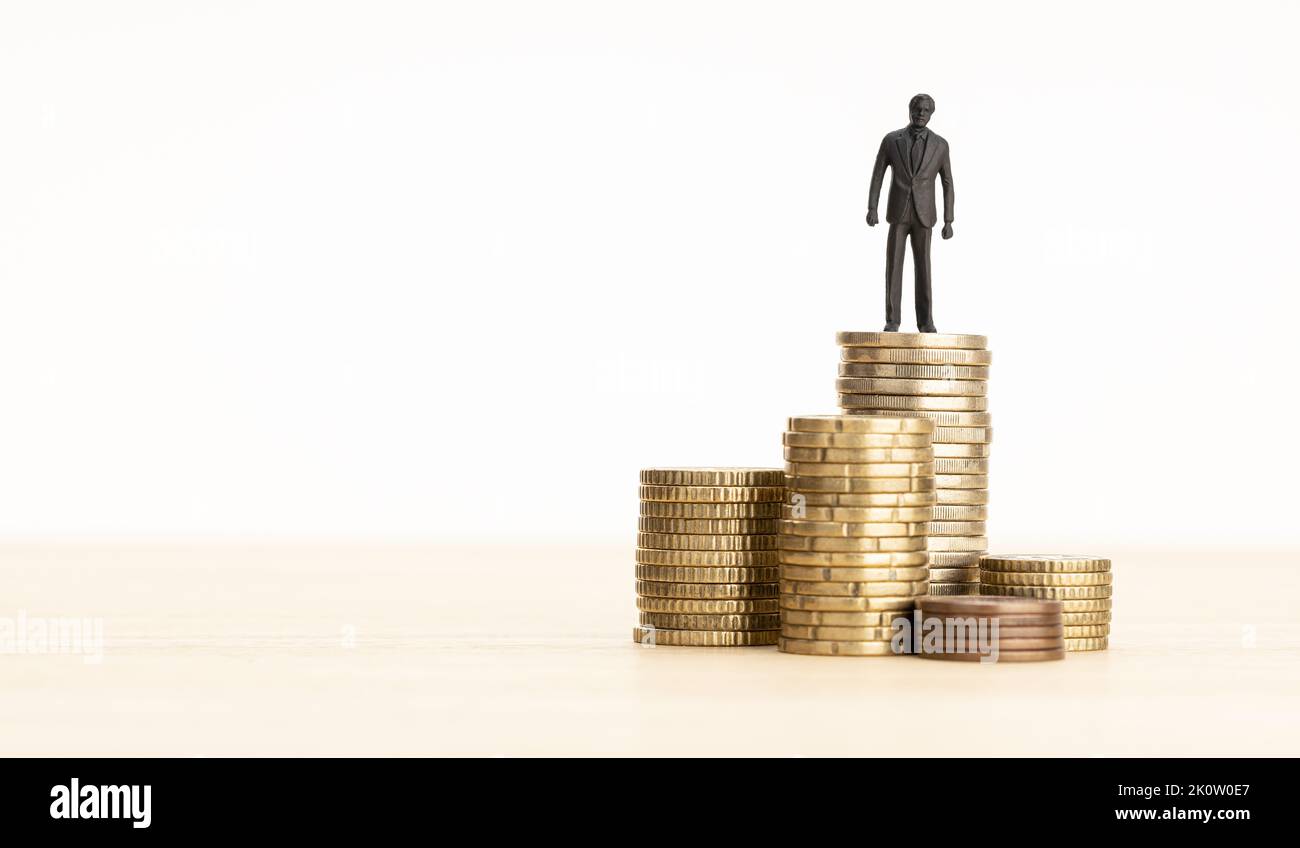 Wealth, making money, wage growth concept. Businessman figurine standing on a pile of coins. Copy space Stock Photo
