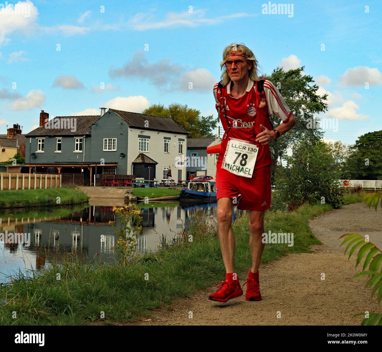Runner no 78 in the Liverpool to Leeds long distance canal race passes a canal side pub near Burscough in West Lancashire on Saturday 27.8.2022 Stock Photo