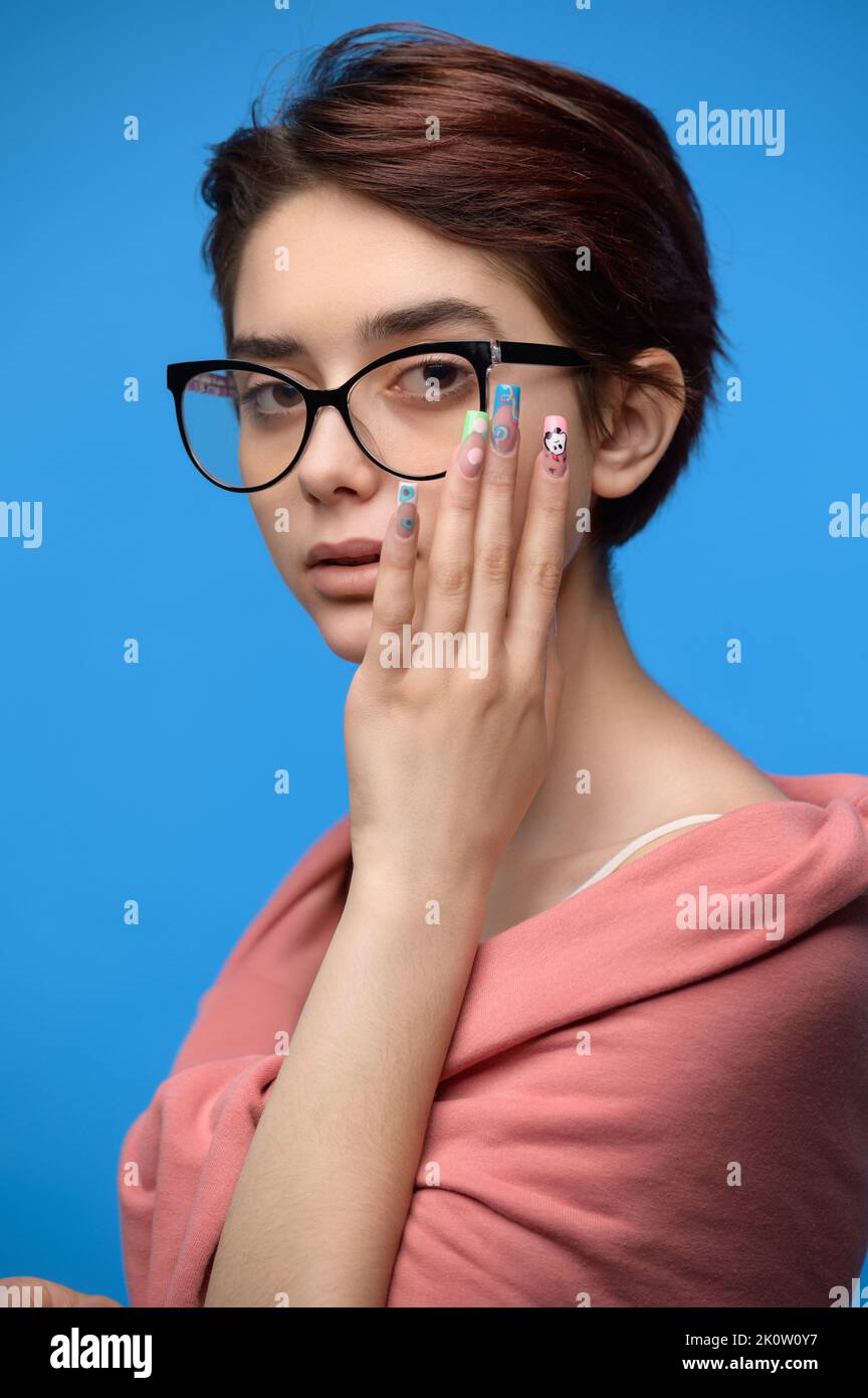Cute female student with short haircut and extravagant nail art Stock Photo