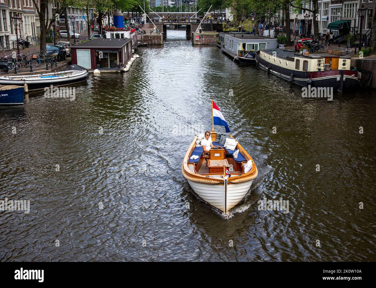 A boat traveling along an Amsterdam canal Stock Photo