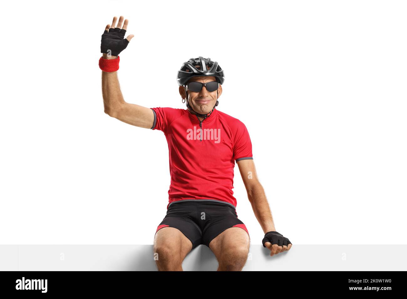 Male cyclist with helmet sitting on a blank panel and waving isolated on white background Stock Photo