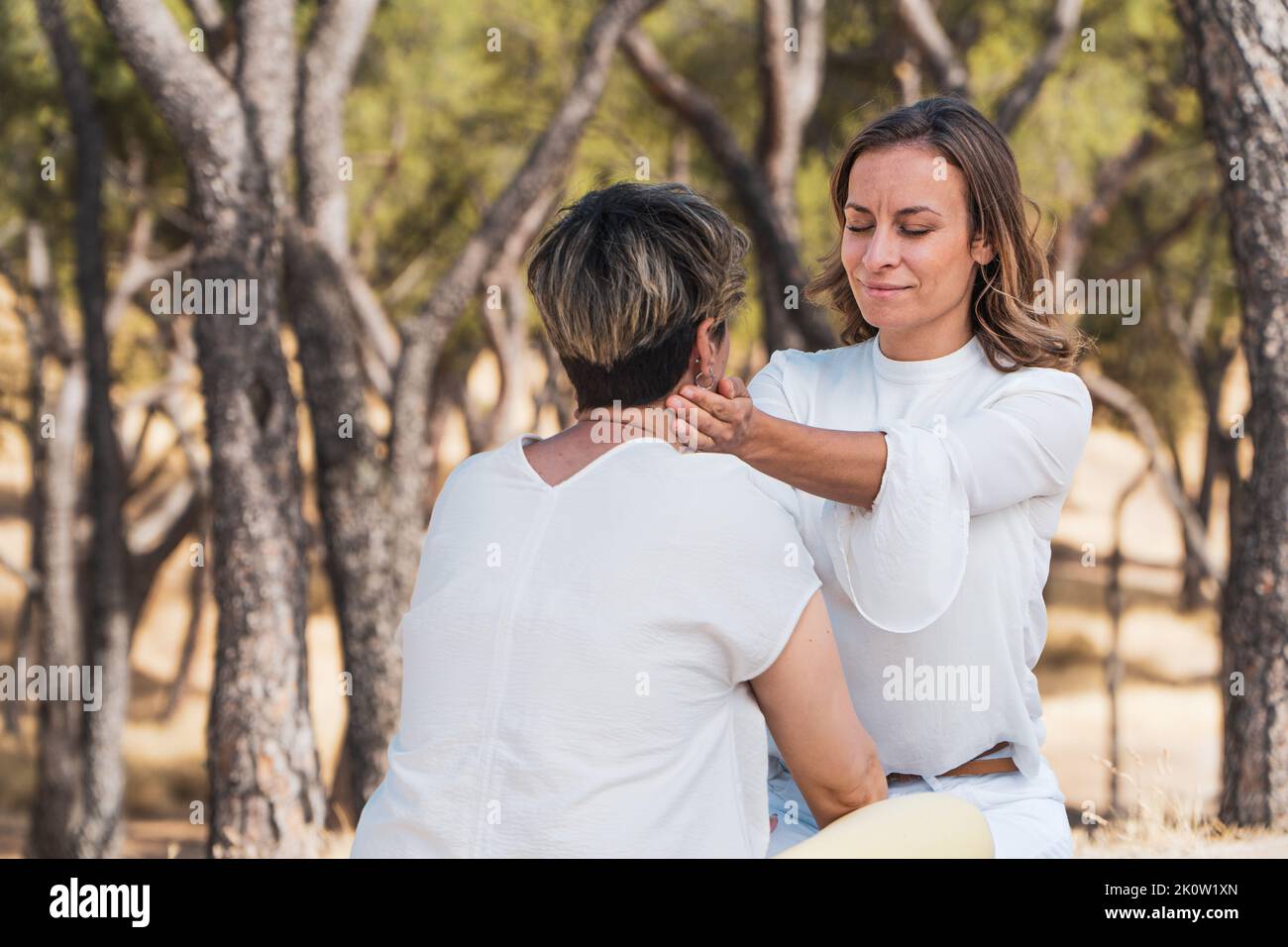 mindfulness coach touching neck of one of the therapy´s participant to help relaxing. women mindfulness therapy on the forest Stock Photo