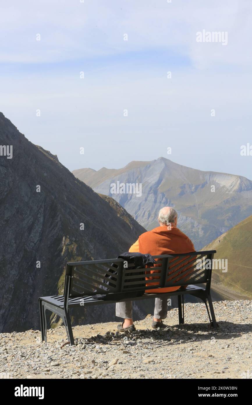 Touriste assis sur un banc observant les Alpes Françaises. Saint-Gervais-les-Bains. Haute-Savoie. Auvergne-Rhône-Alpes. France. Europe. Stock Photo