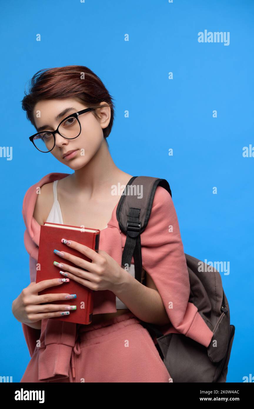 Female student in glasses, with book and backpack Stock Photo