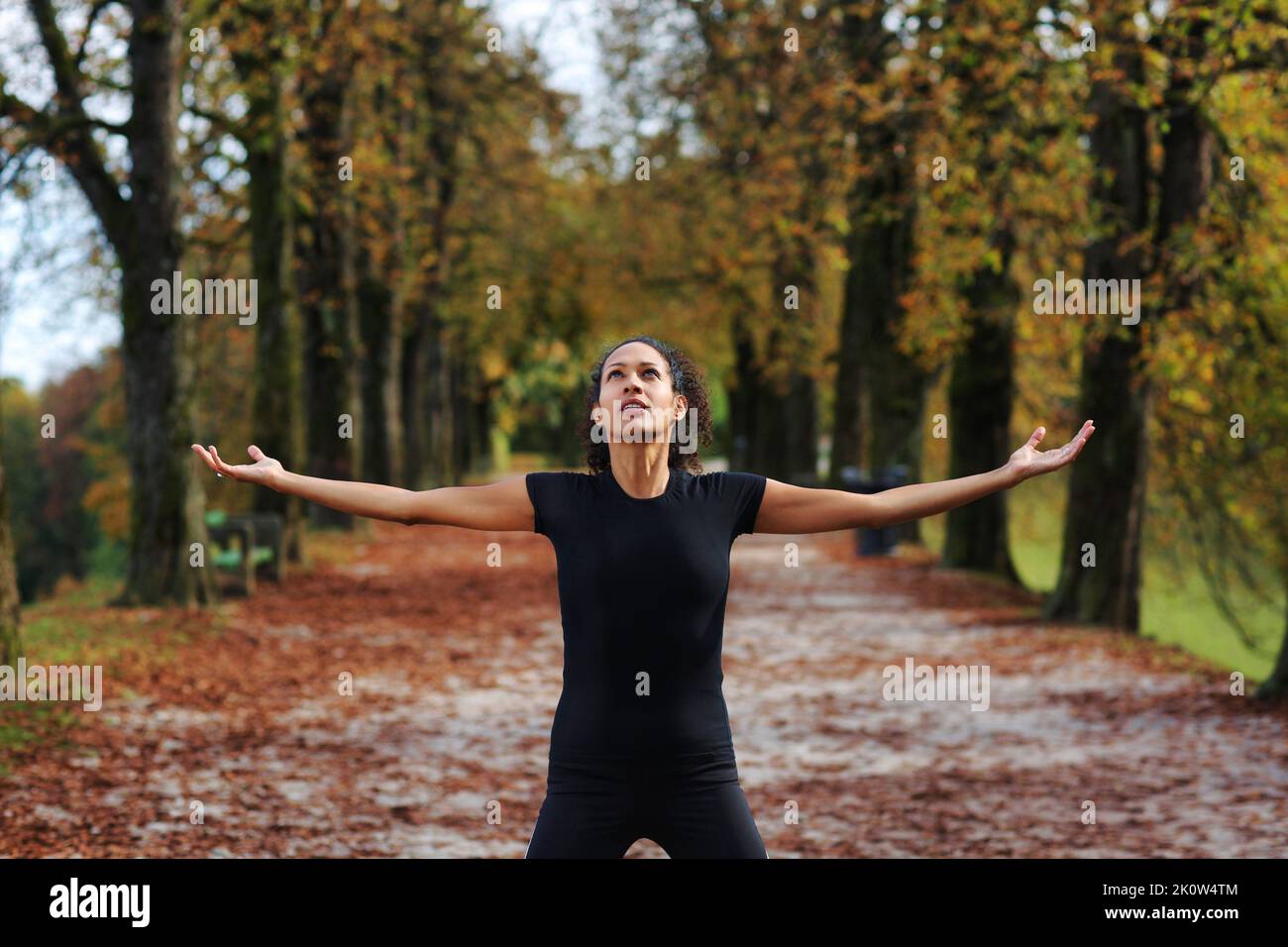 woman outdoors with arms open meditating in sportswear Stock Photo