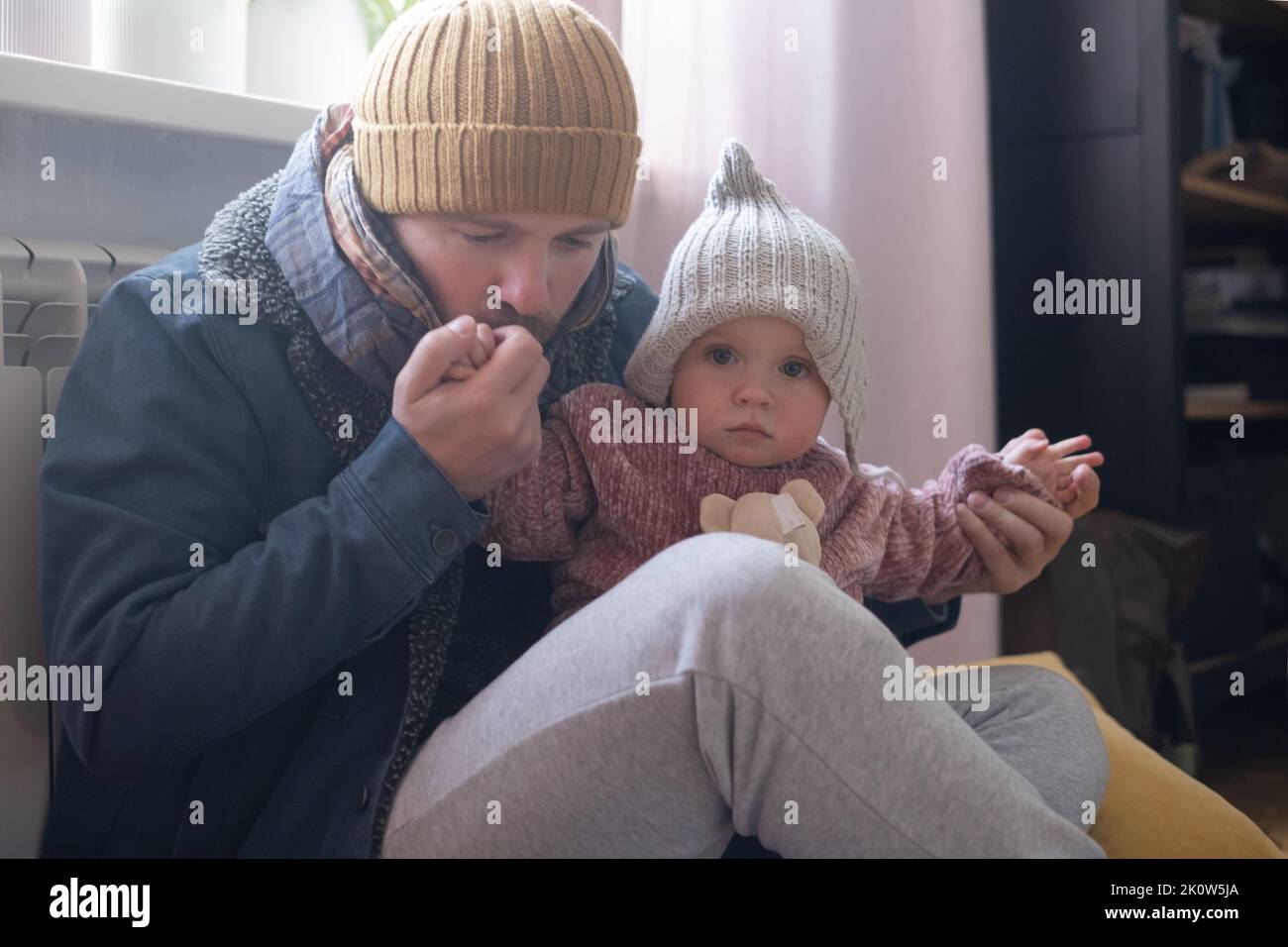 Man wearing warm clothing feeling cold checking central heating battery. Energy crisis in Europe Stock Photo