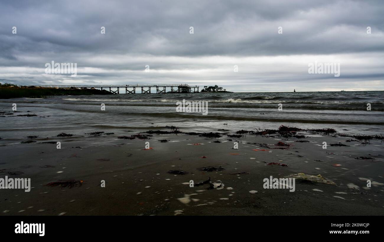 NORWALK, CT, USA - SEPTEMBER 13, 2022 : After storm clouds on beach with fishing pier in distance Stock Photo