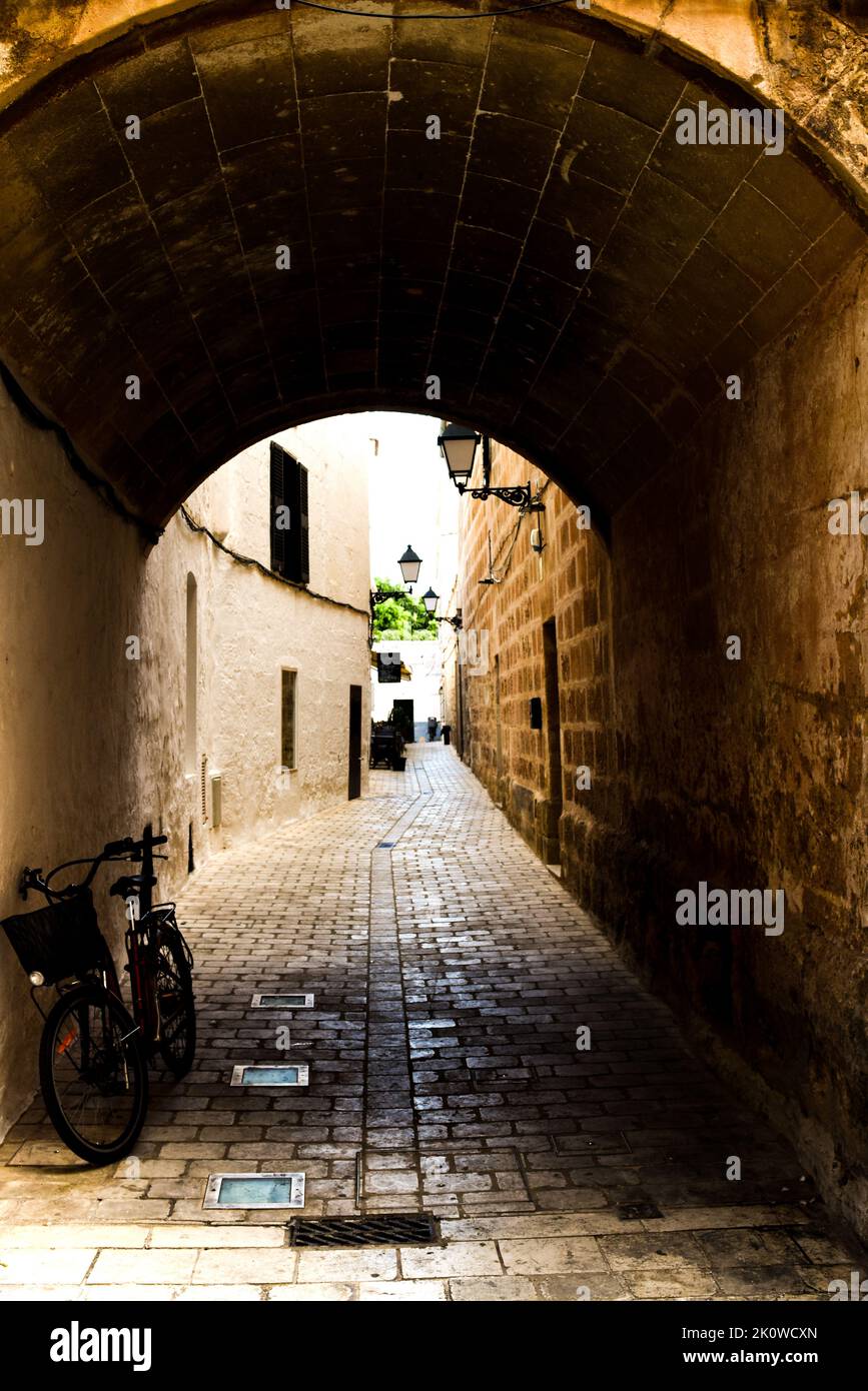 Alley way with arched tunnel leading shops and cafe with bicycle in foreground Stock Photo