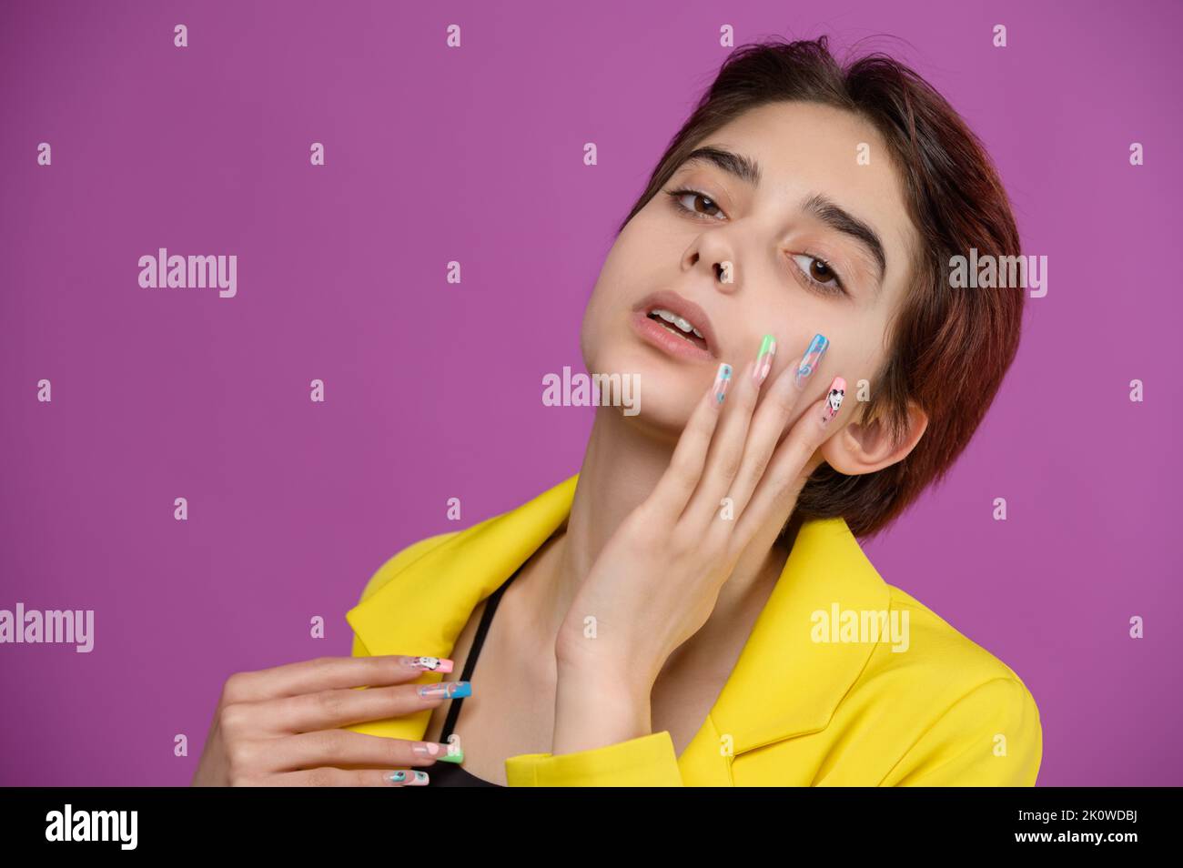 Studio portrait of a young gentle brunette girl with extravagant nail art Stock Photo