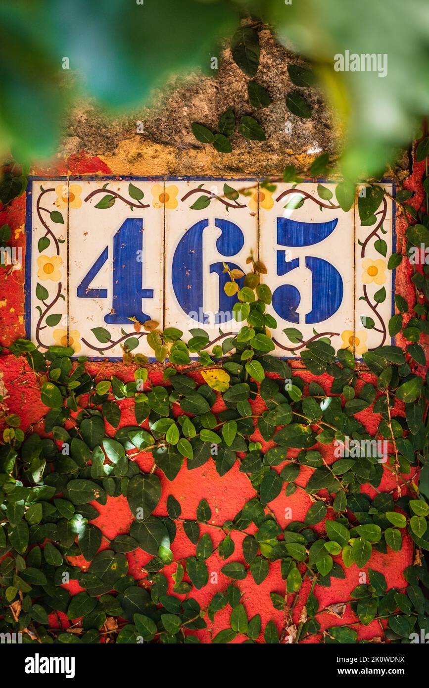Ornate Spanish-style house numbers on ceramic tile covered with vines in Belo Horizonte, Minas Gerais, Brazil. Stock Photo