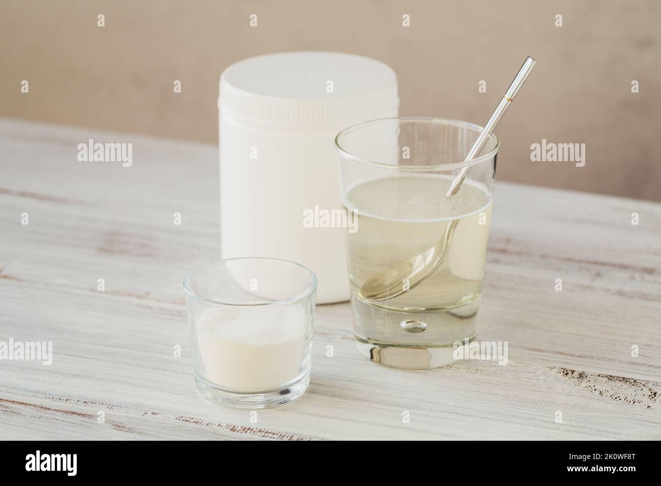 Hydrolyzed marine sourced collagen peptides in glass bowl and water on a white wooden background Stock Photo