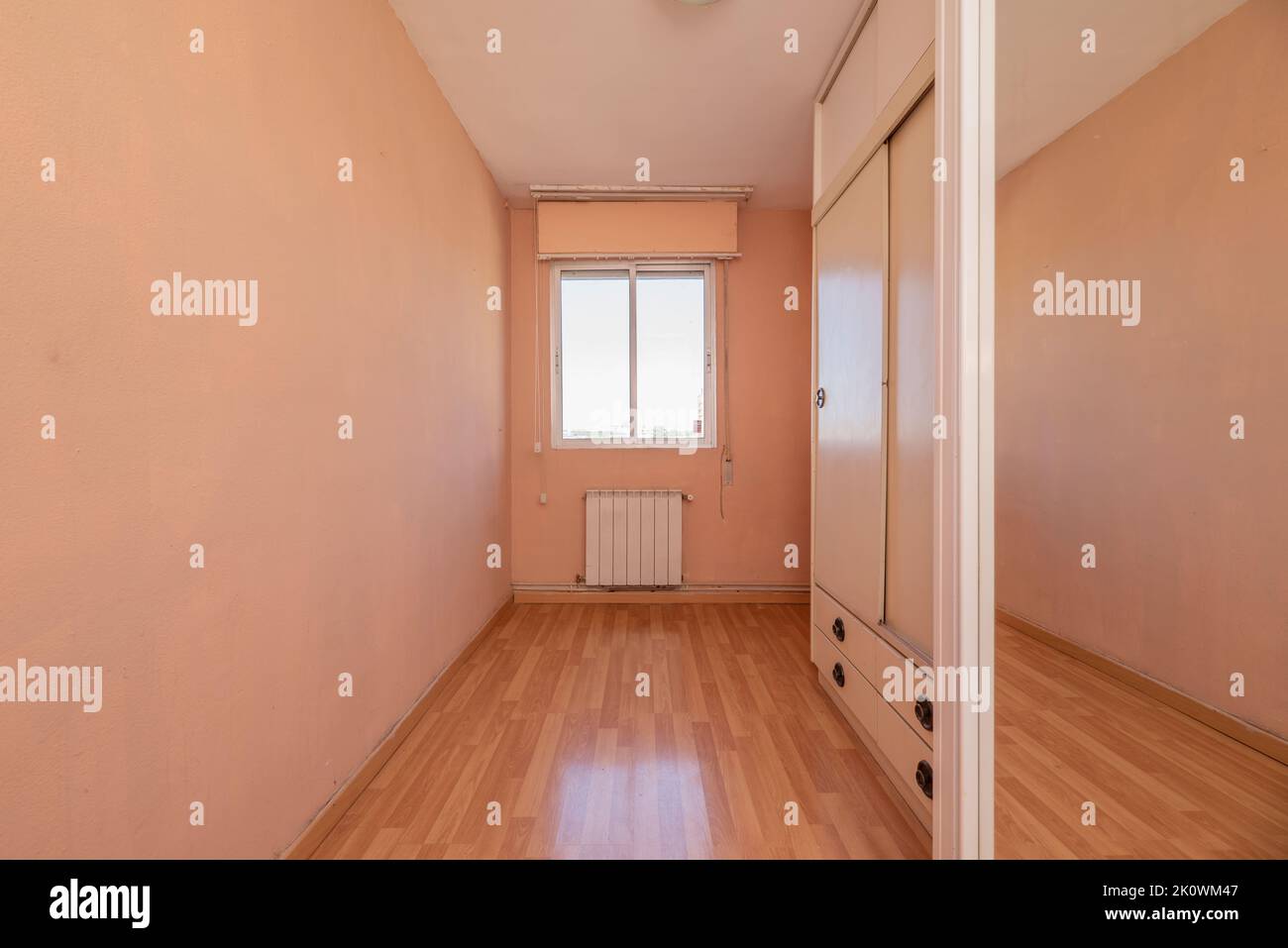 Room with mirrored sliding door wardrobe and glass window and aluminum sheet and pale pink painted walls Stock Photo