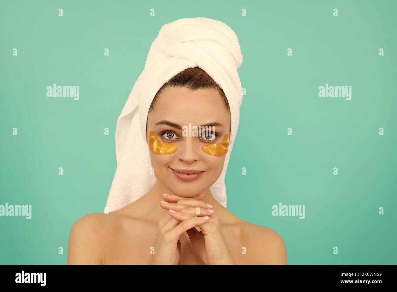 positive young woman has collagen golden eye patches on face with towel Stock Photo Alamy