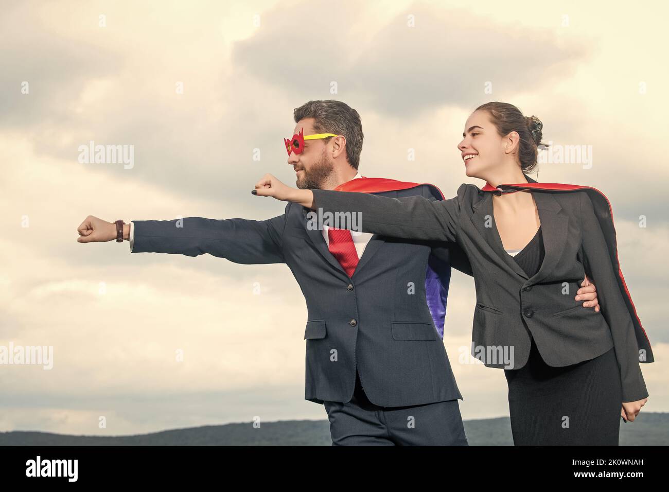 ambitious business couple in superhero suit on sky background Stock