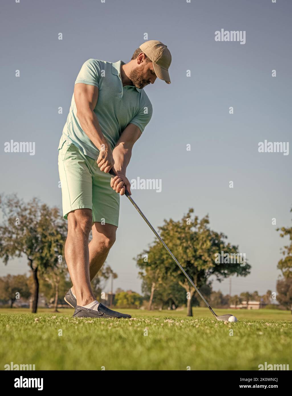 concentrated golfer in cap with golf club, golfing Stock Photo