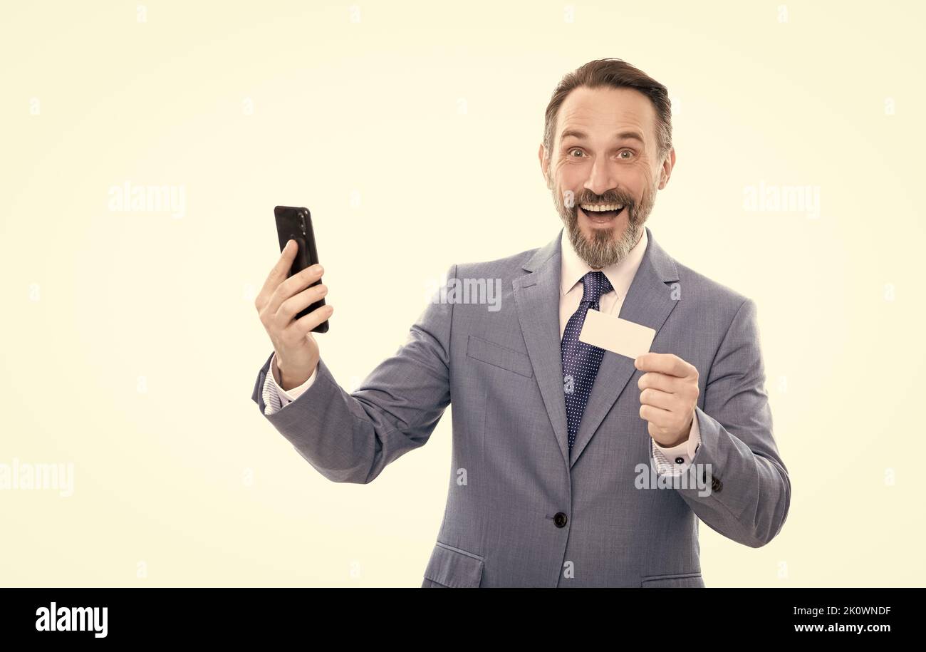 happy mature office manager in suit hold debit card and smartphone isolated on white, internet buy Stock Photo