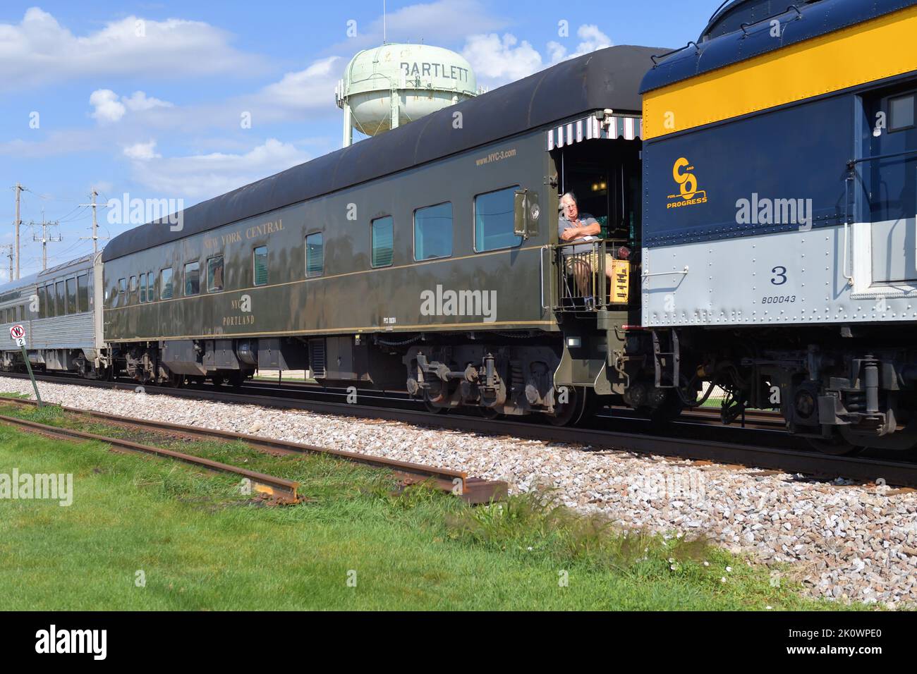 Bartlett, Illinois, USA. Man appears to be sleeping while sitting on a platform of one of the passenger cars making up the AAPRCO special train. Stock Photo
