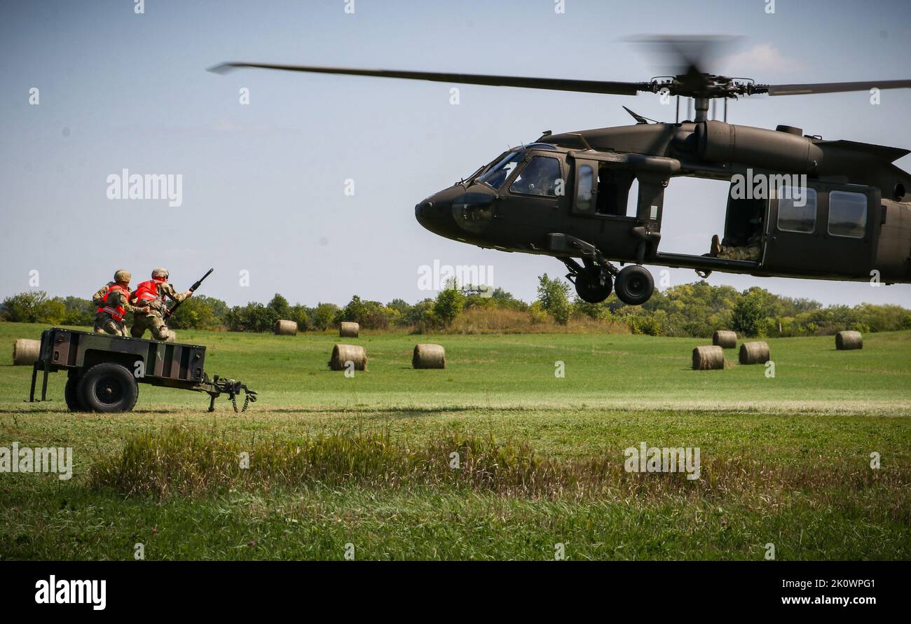 U.S. Army Soldiers prepare to hook up a trailer to an Iowa Army National Guard UH-60 Black Hawk during a sling load exercise as part of a U.S. Pathfinder course at Camp Dodge in Johnston, Iowa, on Sept. 8, 2022. Nearly 30 Soldiers graduated the course, which was taught by a mobile training team at the Army National Guard Warrior Training Center in Fort Benning, Georgia. Army Pathfinders are trained to provide navigational aid and advisory services to military aircraft in areas designated by supported unit commanders. During the Pathfinder course, students are instructed in aircraft orientation Stock Photo