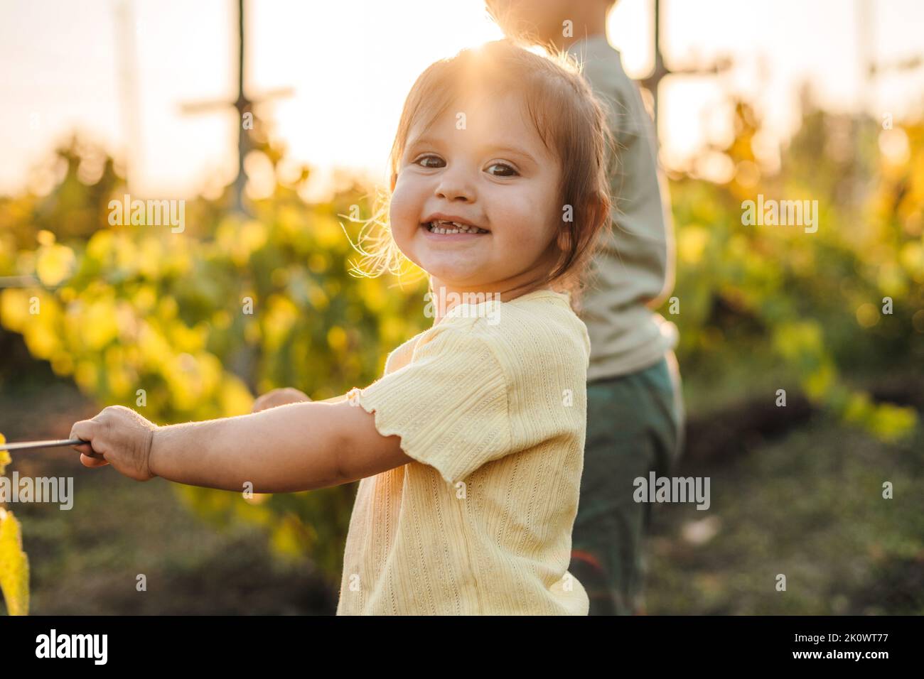 Little adorable baby girl dressed in yellow standing with her brother