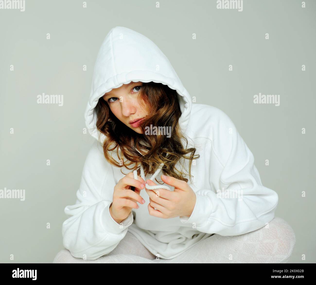 teenage girl in a white hoodie in the studio on a white background stands faces and various grimaces she is beautiful and young. High quality photo Stock Photo Alamy