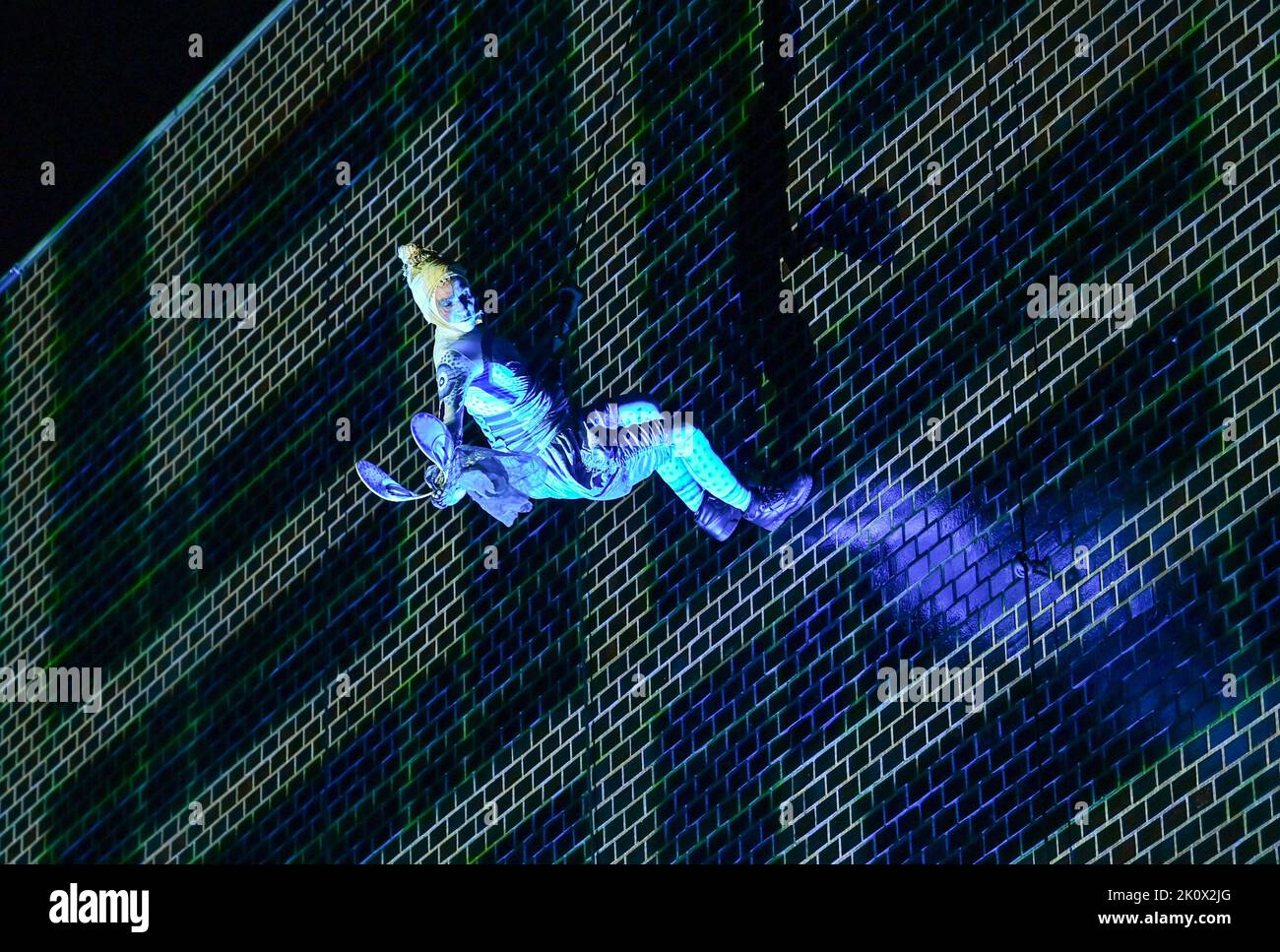 13 September 2022, Brandenburg, Frankfurt (Oder): An actor hangs on a rope in front of the illuminated facade of the Kleist Forum during the rehearsal for the play 'Global Amazonia'. The spectacular facade production is a co-production of the Kleist Forum with Grotest Maru. The play will premiere on Sept. 16, 2022. The artists abseil from the roof of the Kleist Forum and perform on the facade. Video and light projections, live music and vertical theater provide unique images. Thematically, it is about climate change and species extinction and how everything is connected to everything else. Abo Stock Photo