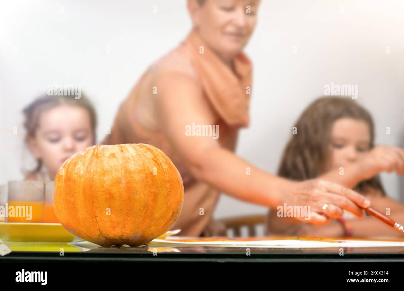 Grandmother with children painting a pumpkin for Halloween Stock Photo