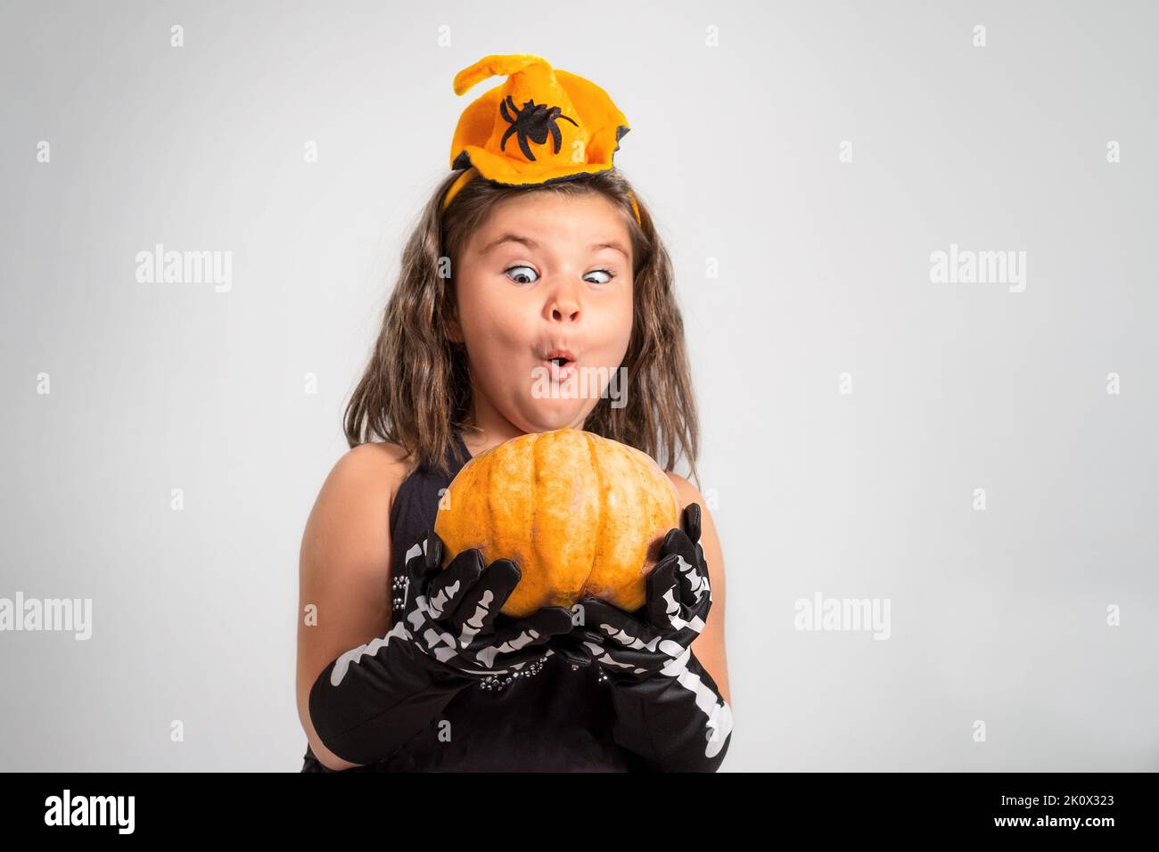 Portrait of a girl with Halloween pumpkin on a gray background Stock Photo