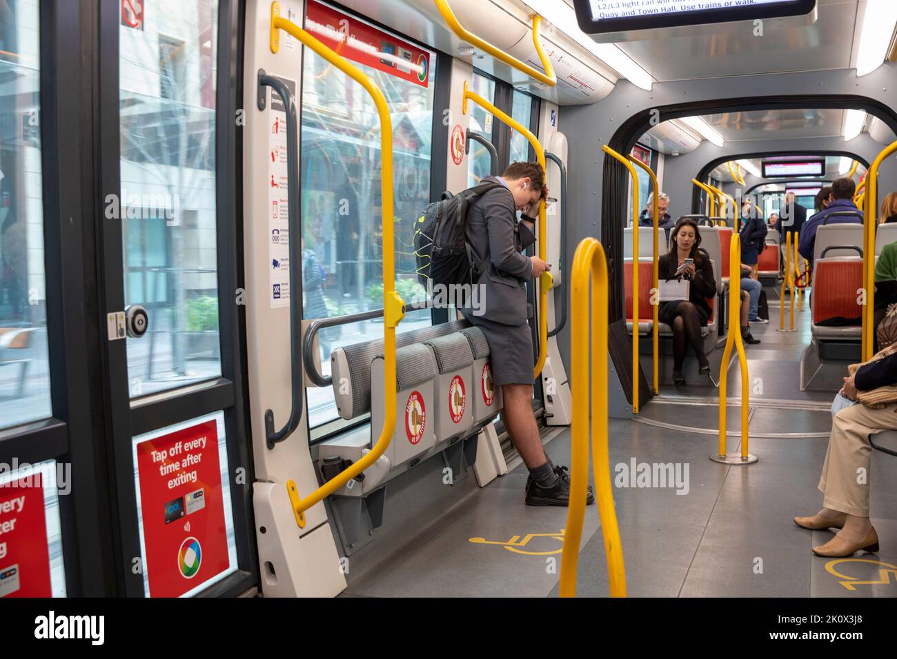Interior of Sydney light rail train carriage with passengers and a school boy standing and sitting,Sydney city centre,NSW,Australia Stock Photo