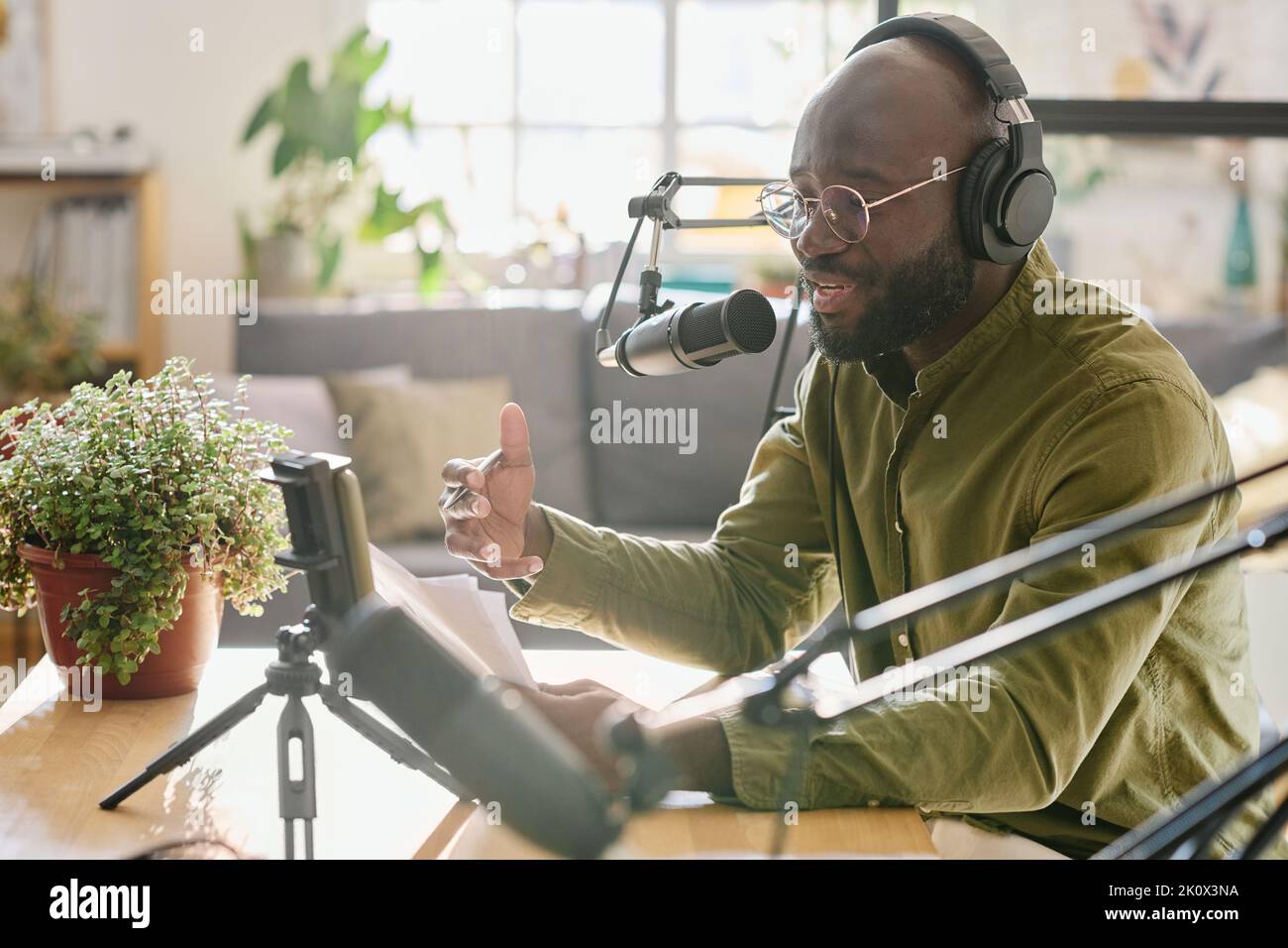 Black guy in headphones talking in microphone while reading plan of