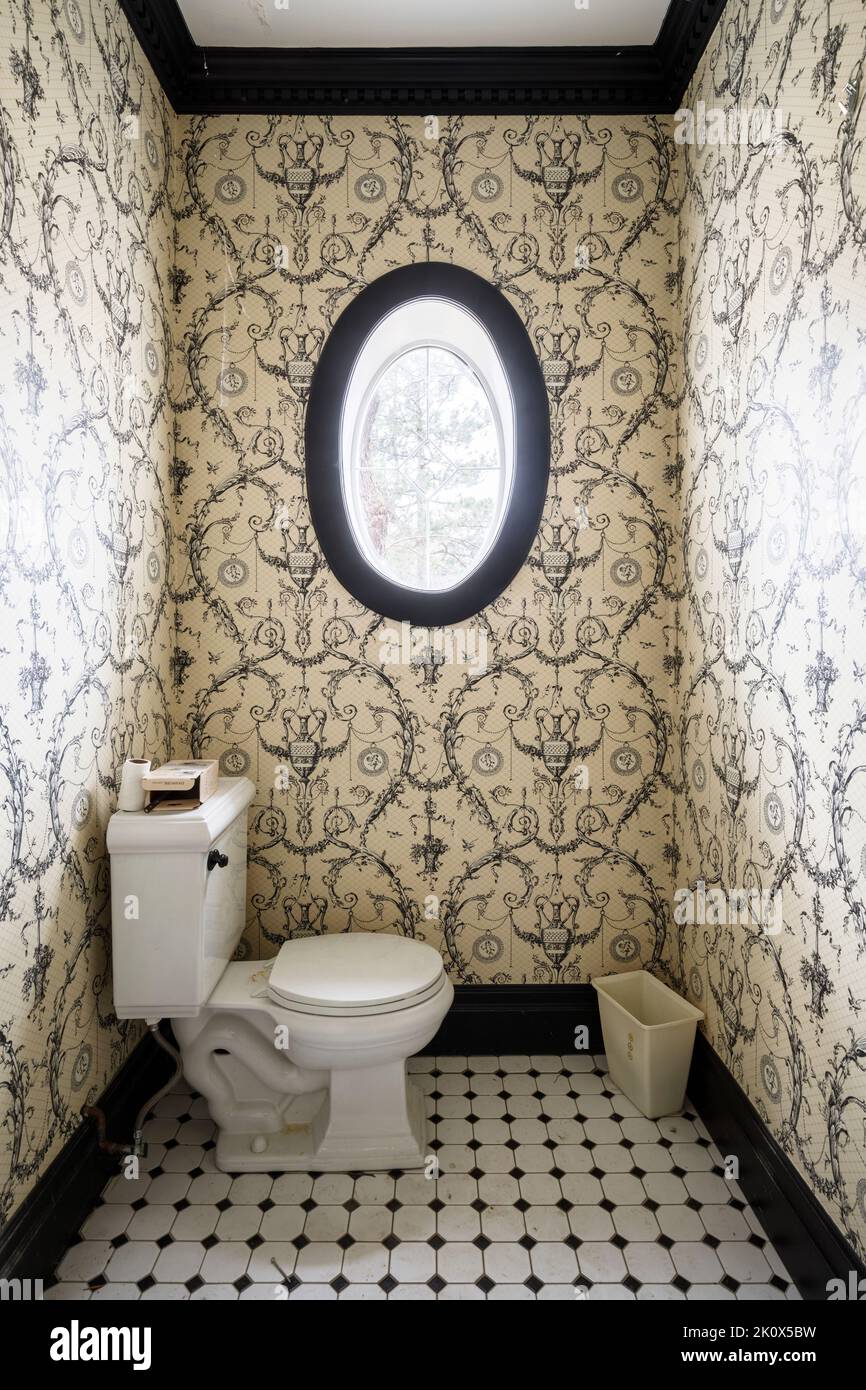 A small bathroom inside a house with an oval shaped window. this home has since been demolished. Stock Photo