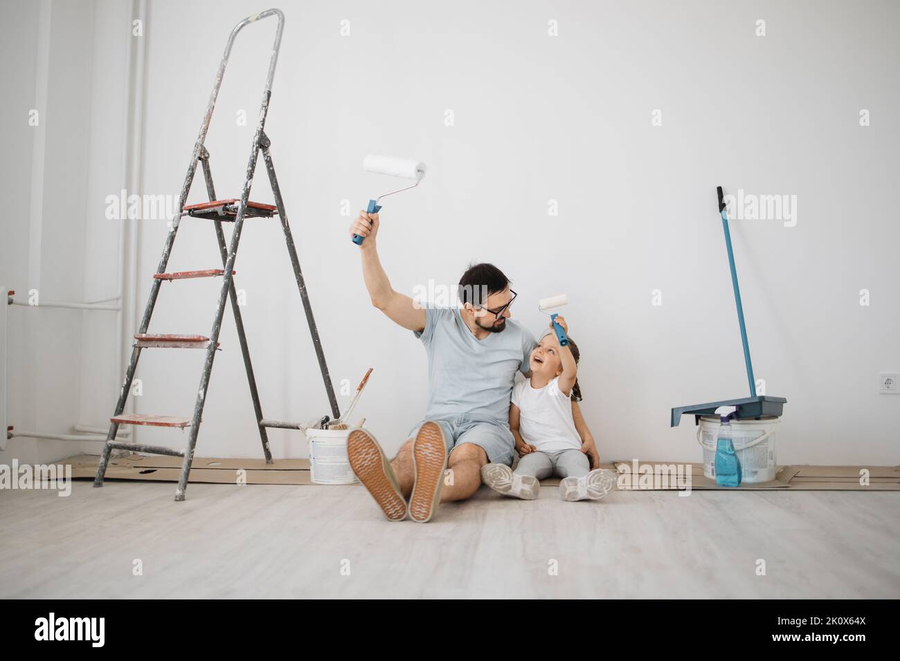 Young father and his little blonde cute girl daughter with wall paint ...
