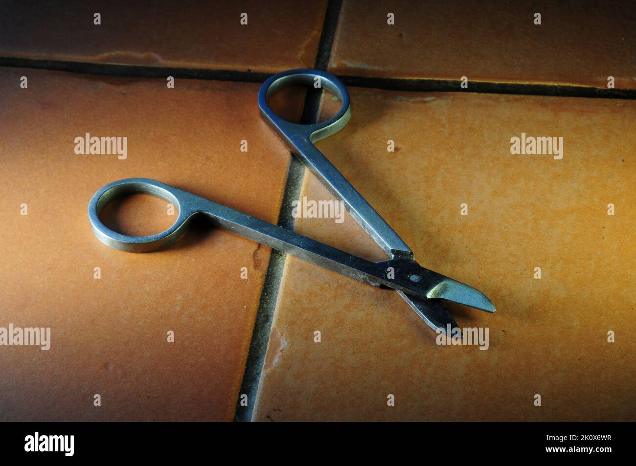 Finger nail scissors on quarry tile surface Stock Photo