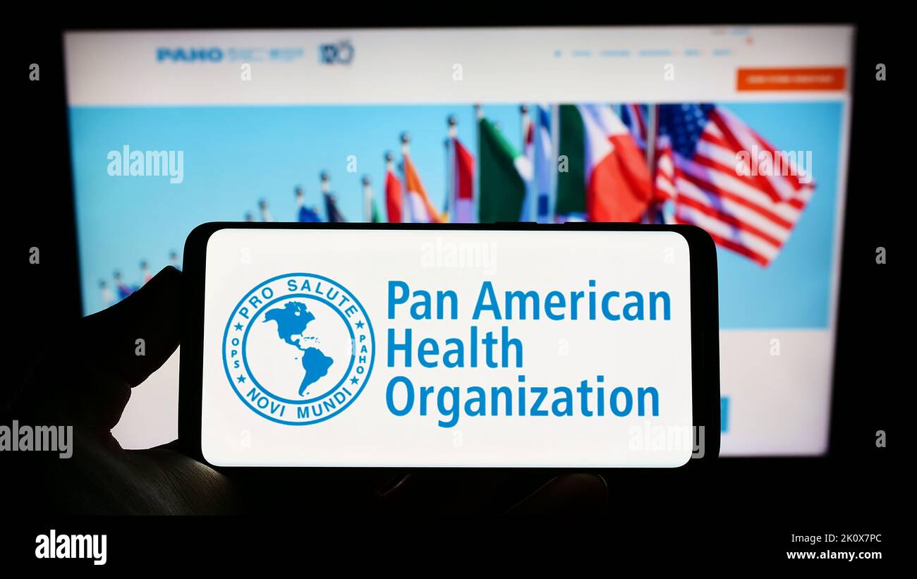 Person holding smartphone with logo of Pan American Health Organization (PAHO) on screen in