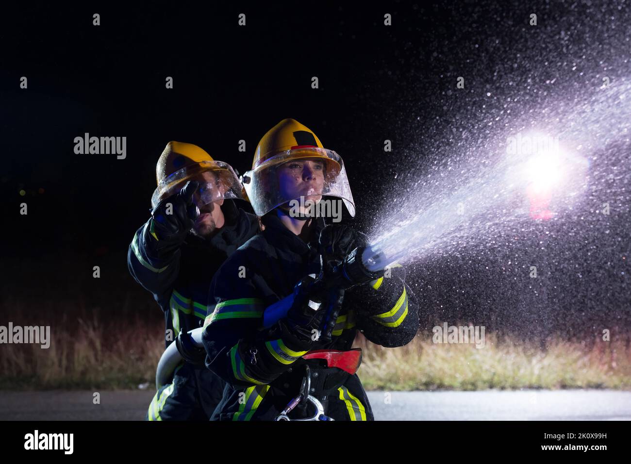 Firefighters using a water hose to eliminate a fire hazard. Team of ...