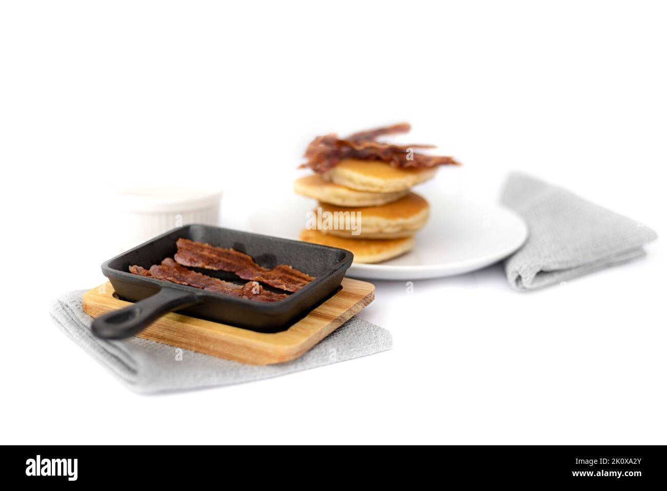 Mini castiron skillet with crispy bacon and pancake stack in the