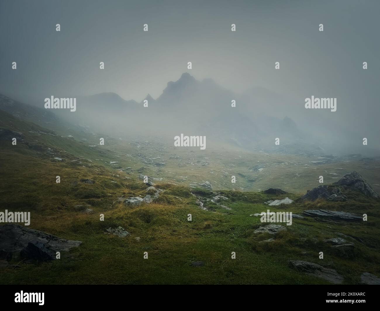 Mountain peak seen through the dense fog. Rainy scene in the mounts, hiking in the mist landscape Stock Photo