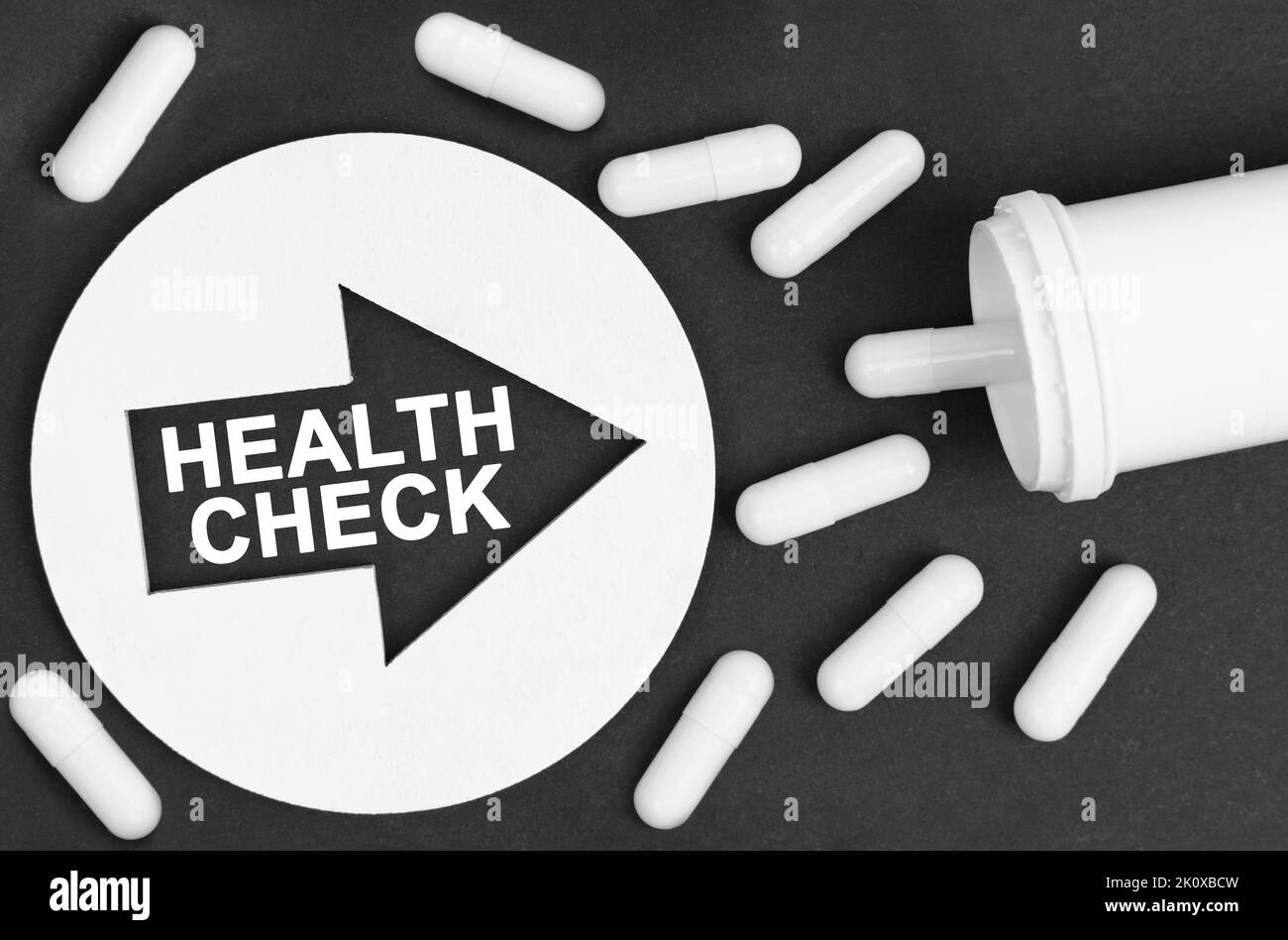 Medicine concept. Pills on a black background. They are indicated by a circle with an arrow, inside which it is written - HEALTH CHECK Stock Photo