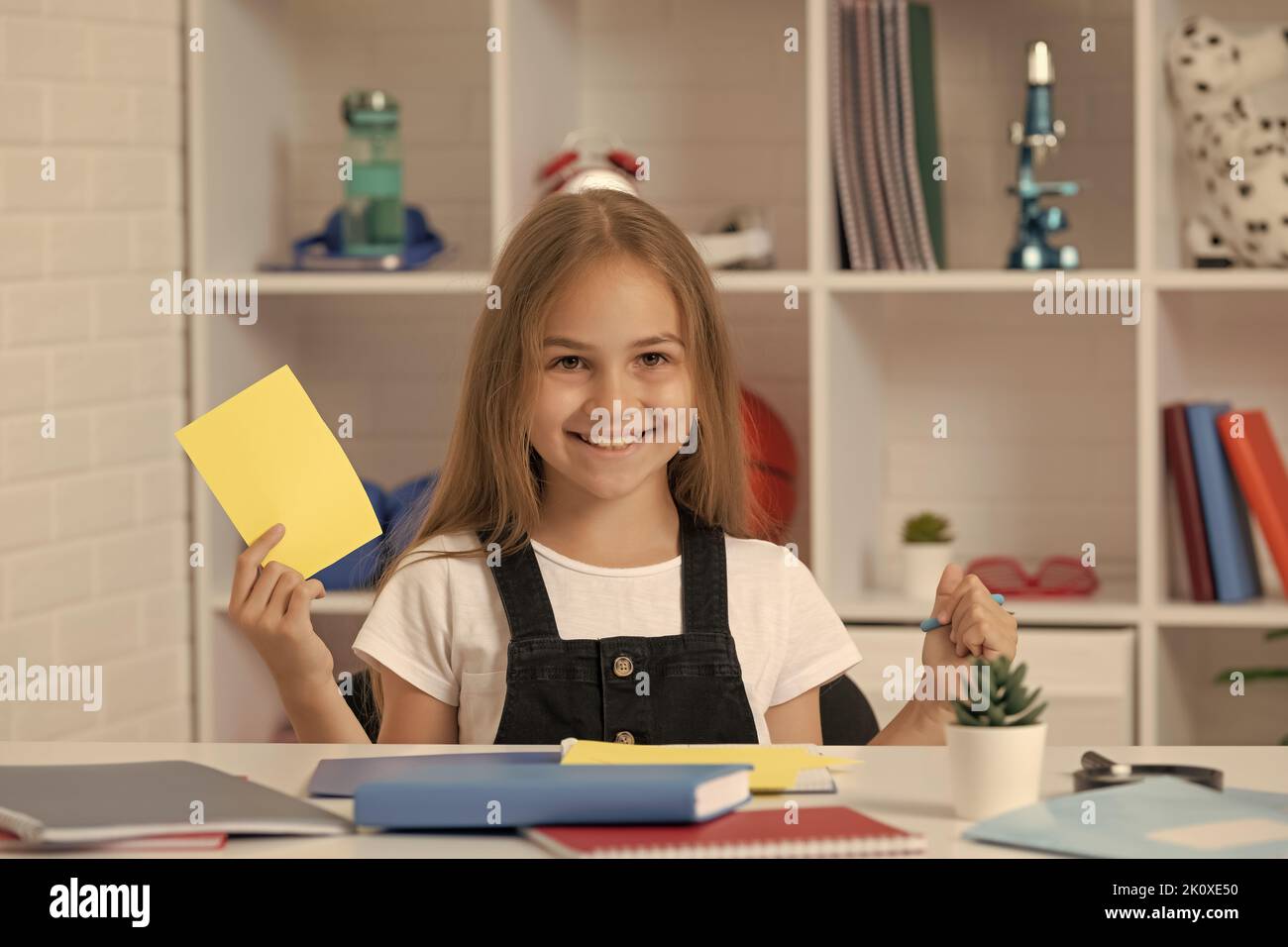 happy child holding paper and scissors in school classroom Stock Photo