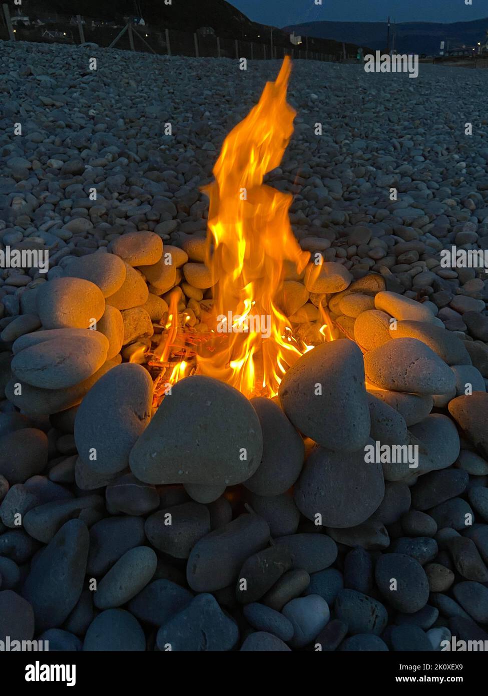 A fire pit on a rocky beach at night Stock Photo