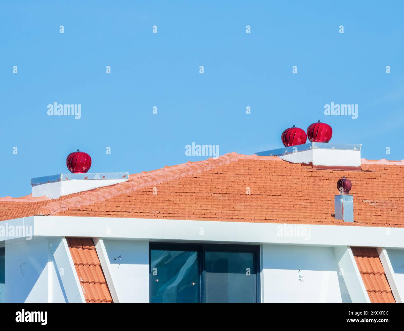 Three red colored turbine vents on the roof of residential building ...