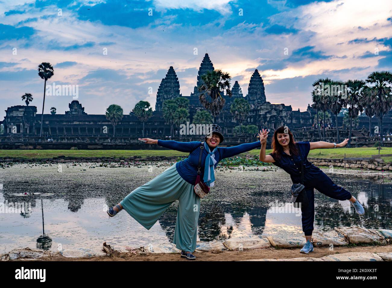 Cambodia. Siem Reap Province. Tourists have their photo taken in front of Angkor Wat (Temple City) and its reflection in the lake at early morning.  A Stock Photo