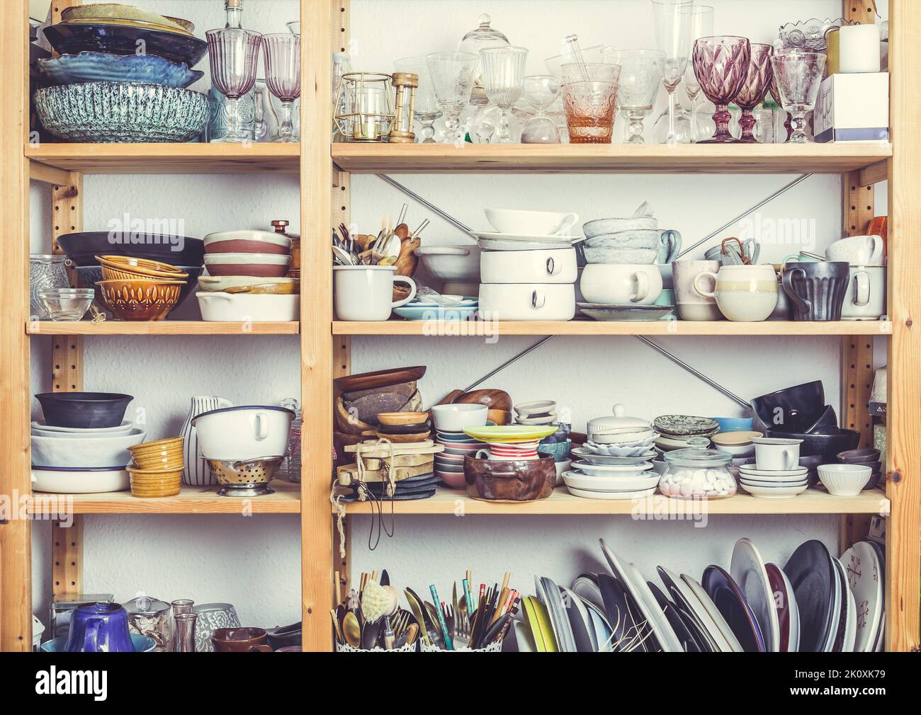 Shelves with kitchen clutter, utensils and kitchenware. Concept of tidying and decluttering Stock Photo