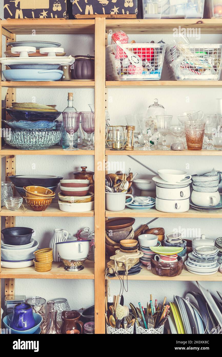 Shelves with kitchen clutter, utensils and kitchenware. Concept of tidying and decluttering Stock Photo