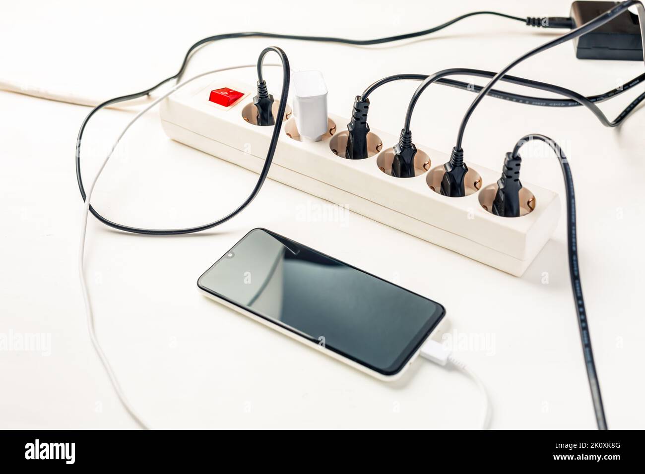 Many chargers plugged into multiple socket. Concept of overloading and energy costs Stock Photo