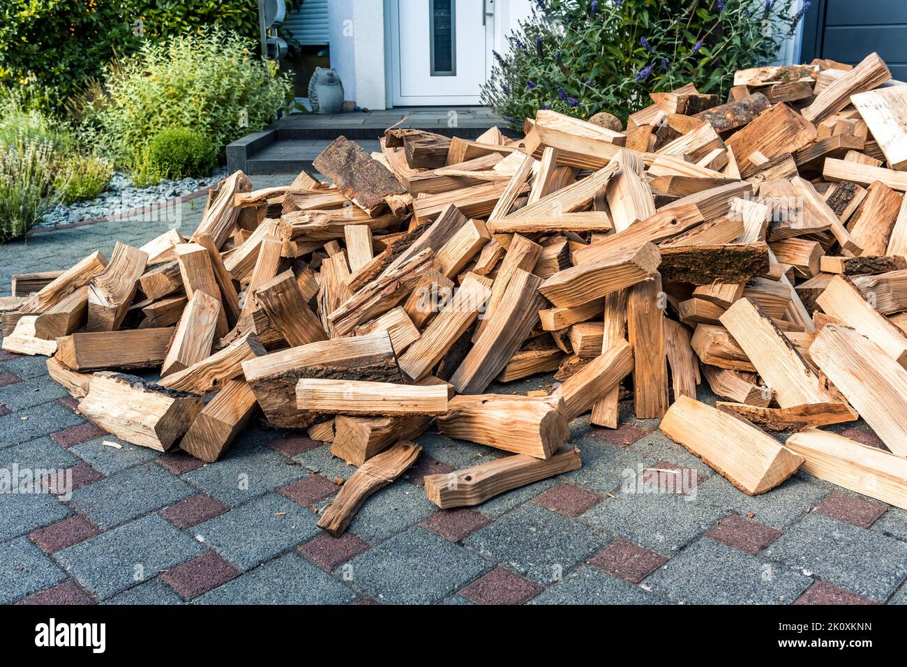Stock of firewood for heating house. Stacked dried logs in front of the house. Stock Photo