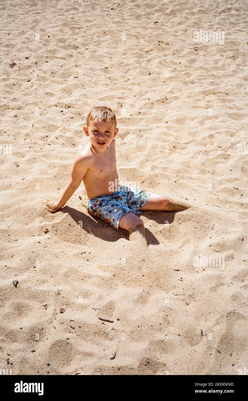 Five year old boy playing in the sand at Hope Cove, Kingsbridge,Devon, England, United Kingdom. Stock Photo