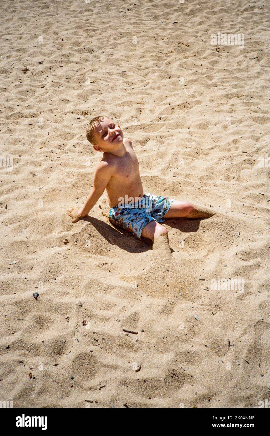 Five year old boy playing in the sand at Hope Cove, Kingsbridge,Devon, England, United Kingdom. Stock Photo